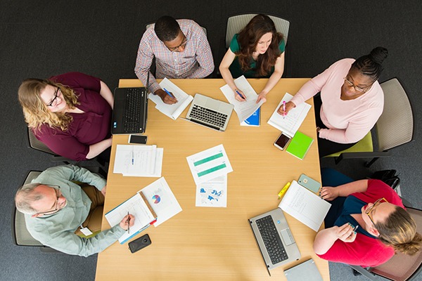 group of people sitting in a circle at a conference room table